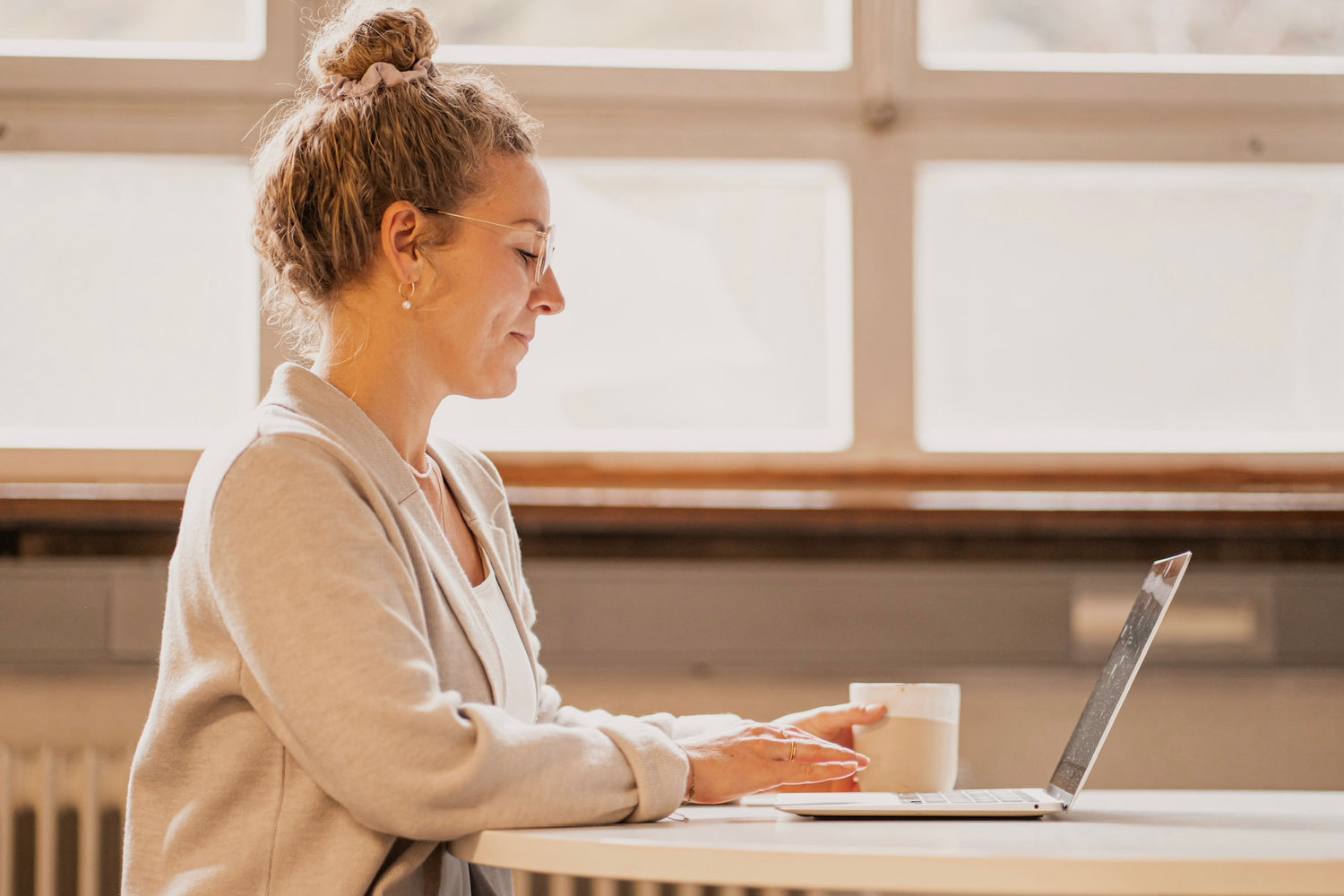 Anja von Imkerei Ostermann bei der Shop-Pflege, vor einem Laptop sitzend mit Kaffeetasse in der Hand. 