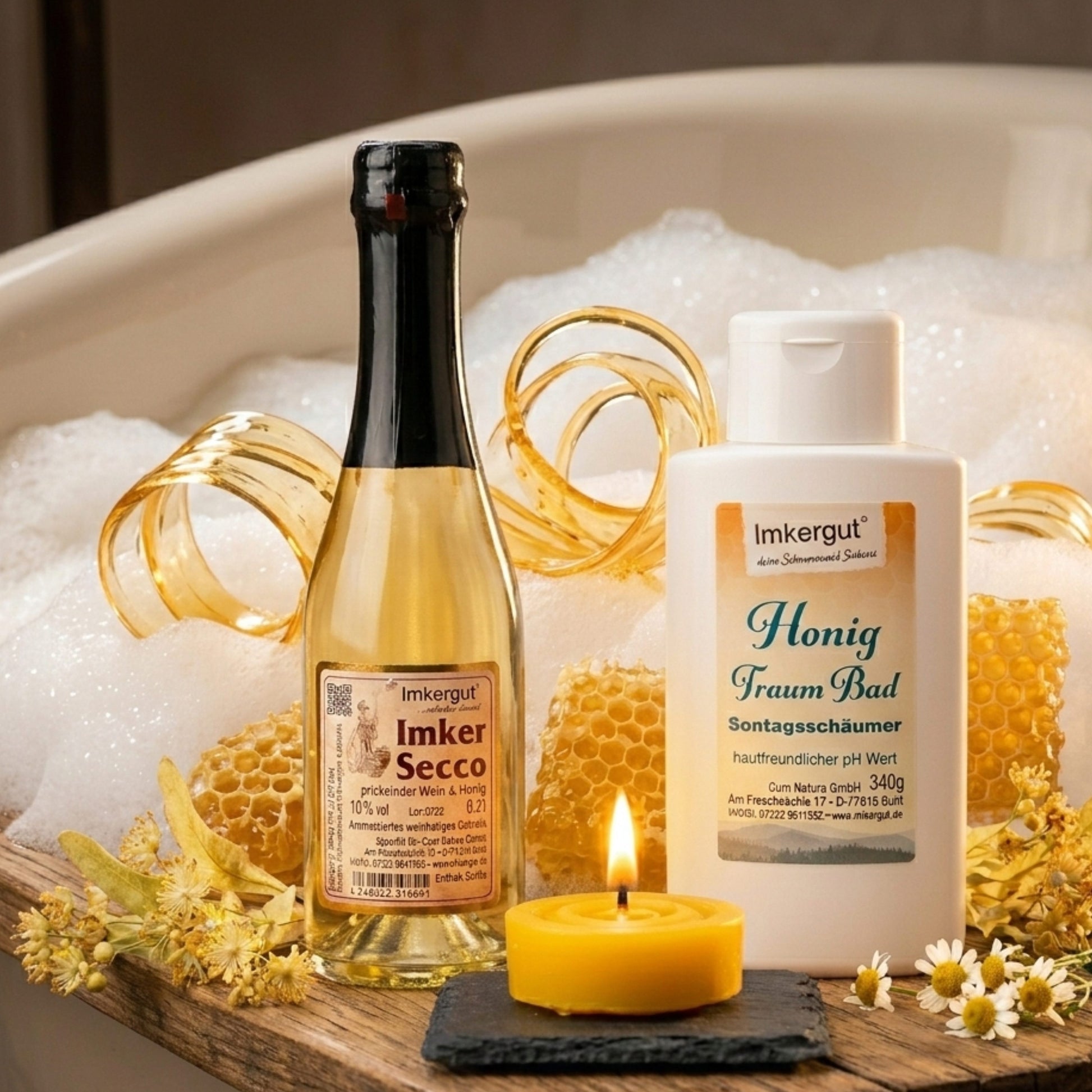 Geschenkset Goldene Auszeit der Imkerei Ostermann mit einer Flasche Imker-Secco, einer Flasche Honig-Traumbad und einer handgegossenen Bienenwachskerze auf einem Holzbrett vor einer Badewanne mit Schaum, dekoriert mit goldenen Honigwaben-Segmenten, Lindenblüten und Kamille.